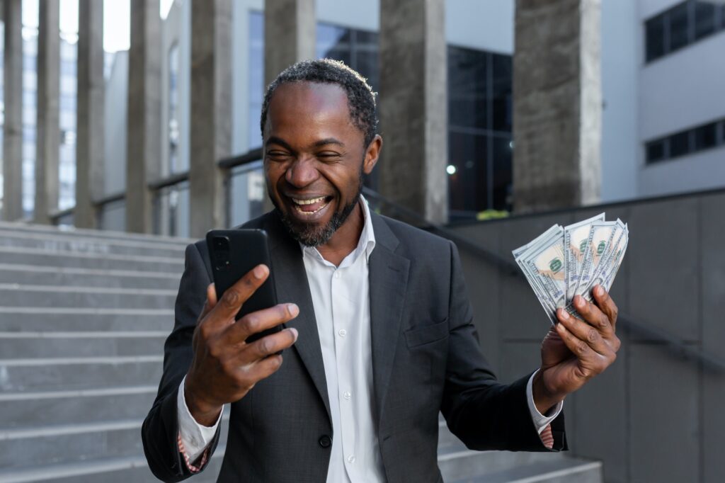 African american man in business suit rejoices, got online small business loan, owner with money